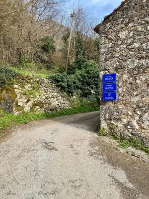 a road with a blue sign next to a stone wall at Skadar Lake House Nature Nest in Virpazar
