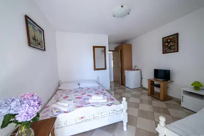 a small bedroom with a bed and a table at Apartments Vila Nikolić Rafailovići in Rafailovici