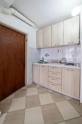 a kitchen with wooden cabinets and a brown door at Apartments Vila Nikolić Rafailovići in Rafailovici
