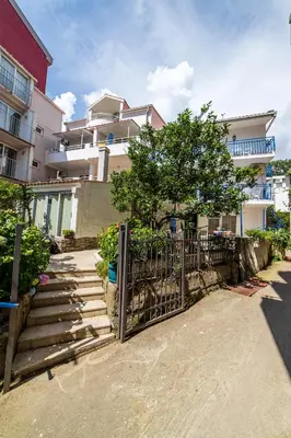 a fence in front of a building with a tree at Apartments Vila Nikolić Rafailovići in Rafailovici
