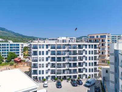an apartment building with cars parked in a parking lot at Vienna Luxury Apartments in Dobra Voda