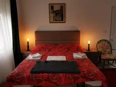 a bedroom with a red bed with two pillows on it at In Apartments AirPort in Mitrovići