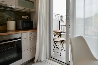 a kitchen with a microwave and a balcony with a table at TriA Studio in Bar