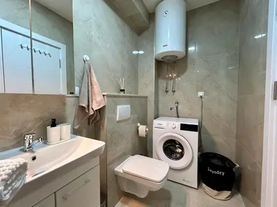a bathroom with a toilet and a washing machine at TriA Studio in Bar