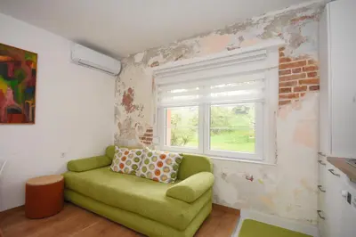 a green couch in a room with a window at Brick house in Cetinje