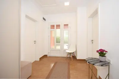 a white hallway with a chair and a window at Brick house in Cetinje