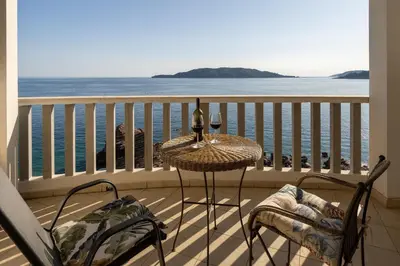 a table and chairs on a balcony overlooking the ocean at Net in Rafailovici