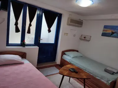 a room with a bed and a table and a window at Bay Mola Home in Kotor