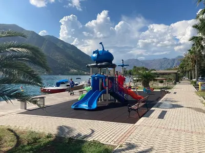 a playground with a slide next to the water at Bay Mola Home in Kotor