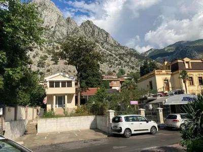 a white car parked in a parking lot in front of a mountain at Bay Mola Home in Kotor