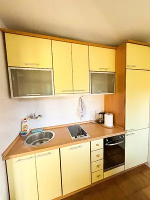 a small kitchen with yellow cabinets and a sink at Mia Apartment in Budva