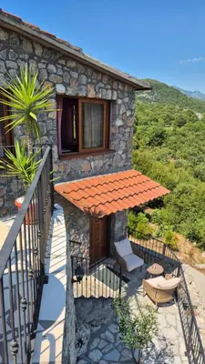 a stone house with a table and a balcony at Rooms Dujeva Drago-Resort in Rijeka Crnojevića