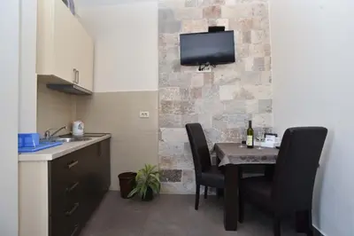 a kitchen with a table with chairs and a tv on a wall at Apartments Jelušić in Budva