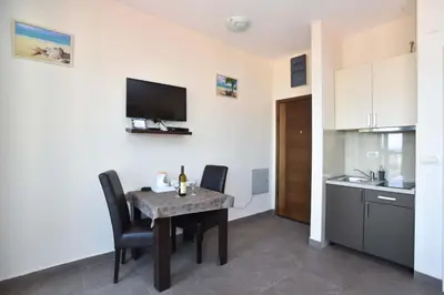 a dining room with a table and chairs and a kitchen at Apartments Jelušić in Budva