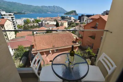 a glass table on a balcony with a bottle of wine at Apartments Jelušić in Budva