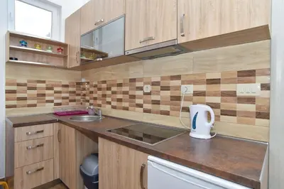 a small kitchen with wooden cabinets and a sink at Apartments Jelušić in Budva