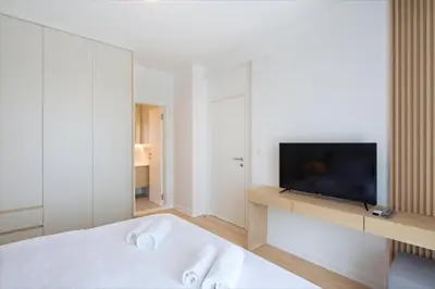 a white bedroom with a tv and a bed at Villa Fotinia in Budva
