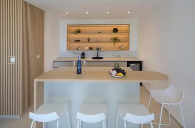 a kitchen with a counter with white stools at Villa Fotinia in Budva