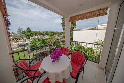 a balcony with a table with red chairs and purple flowers at Apartment Marcic in Bar