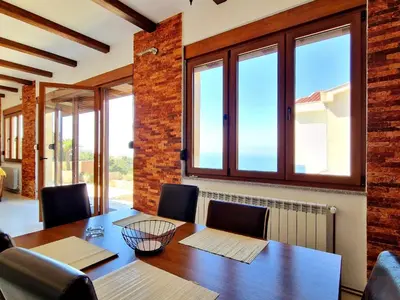 a dining room with a table and chairs and windows at Luxury Villa Pontus in Kotor