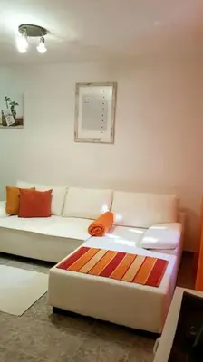 a living room with a white couch with orange pillows at Apartment with a garden Petrovac in Petrovac na Moru