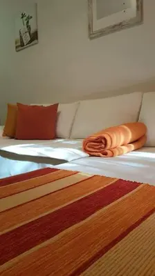 a bed with two orange pillows on top of it at Apartment with a garden Petrovac in Petrovac na Moru