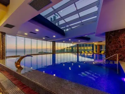 a large swimming pool in a building with a view of the ocean at Tecasi Lux Apartments in Budva
