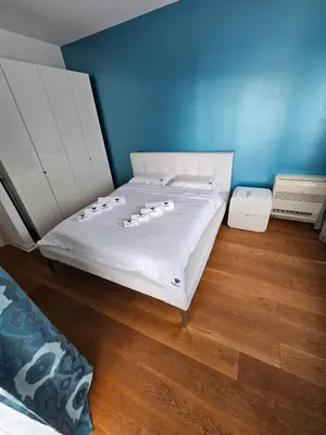a bedroom with a white bed with a blue wall at Tecasi Lux Apartments in Budva