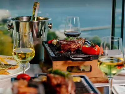 a steak on a grill with two glasses of wine at Tecasi Lux Apartments in Budva