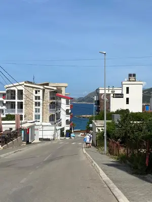 two people sitting on the side of a street with buildings at Sunrise apartmani in Bar