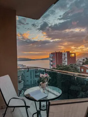 a balcony with a table and chairs and a sunset at Vanja apartment Przno in Budva