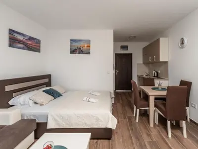 a bedroom with a bed and a table and a kitchen at Apartments 4U in Dobra Voda