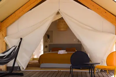 a tent bedroom with a bed and chairs at Oblun Eco Resort - New Glamping Tents near Lake Skadar in Podgorica