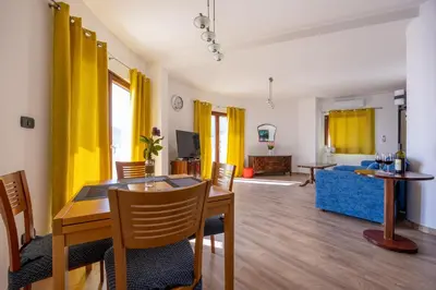 a living room with a dining table and yellow curtains at Adrian in Rafailovici