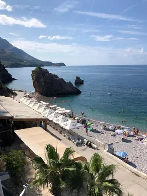 a beach with a bunch of people in the water at Adrian in Rafailovici