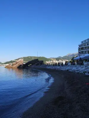 a beach with white chairs and buildings and the water at Adrian in Rafailovici