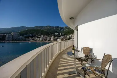 a balcony with a table and chairs and the water at Adrian in Rafailovici