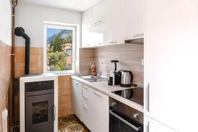 a small kitchen with white cabinets and a window at Apartment Busola in Kotor