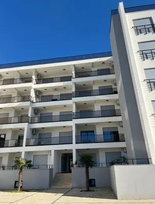 an apartment building with two palm trees in front of it at Oceans Apartman in Dobra Voda