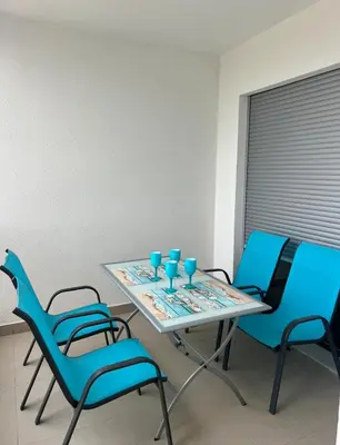 a table with blue chairs and blue glasses on it at Oceans Apartman in Dobra Voda