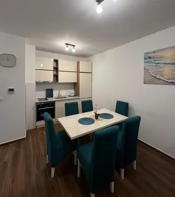 a dining room with a table and blue chairs at Oceans Apartman in Dobra Voda