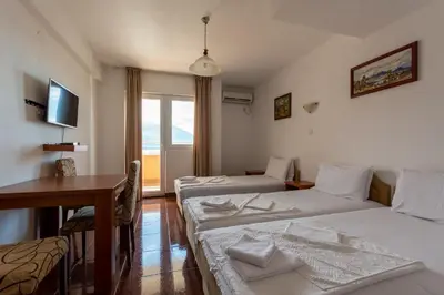 a room with two beds and a table and a desk at Evropa Lux Apartments in Budva