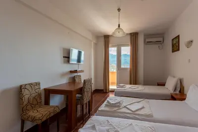a room with two beds and a desk and a window at Evropa Lux Apartments in Budva