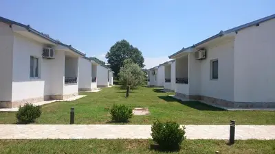 a row of white buildings with grass and trees at Beni Bungalows in Ulcinj