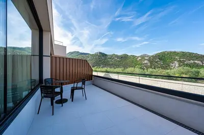 a balcony with a table and chairs and a view of mountains at Hotel De‘Andros Virpazar in Virpazar