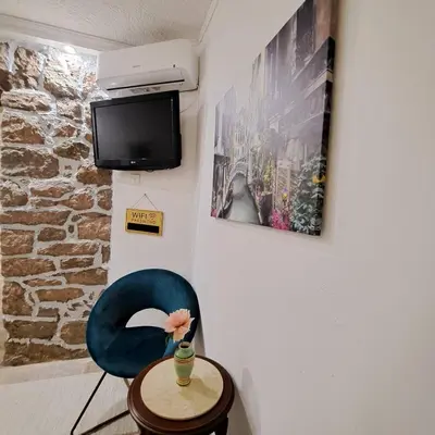 a room with a blue chair and a table and a tv at Unique Apartment Centar in Podgorica