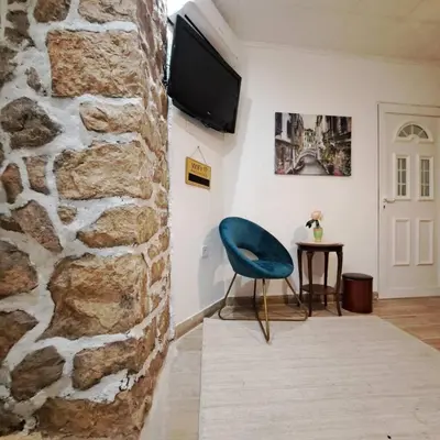 a room with a blue chair next to a stone wall at Unique Apartment Centar in Podgorica