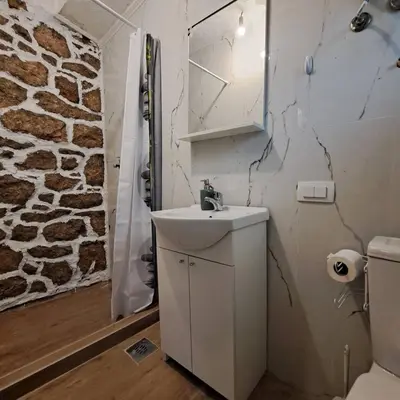 a bathroom with a sink and a stone wall at Unique Apartment Centar in Podgorica