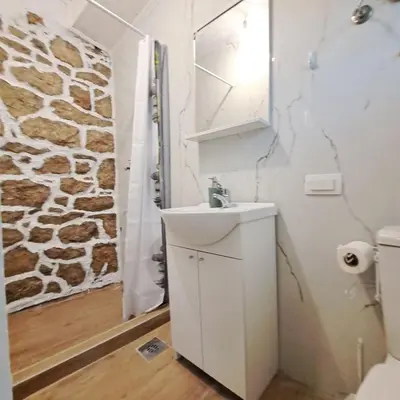 a bathroom with a sink and a stone wall at Unique Apartment Centar in Podgorica