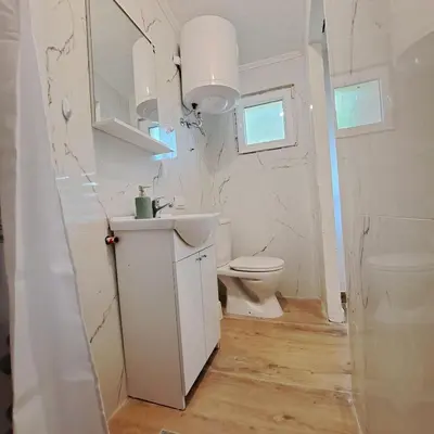 a white bathroom with a toilet and a sink at Unique Apartment Centar in Podgorica